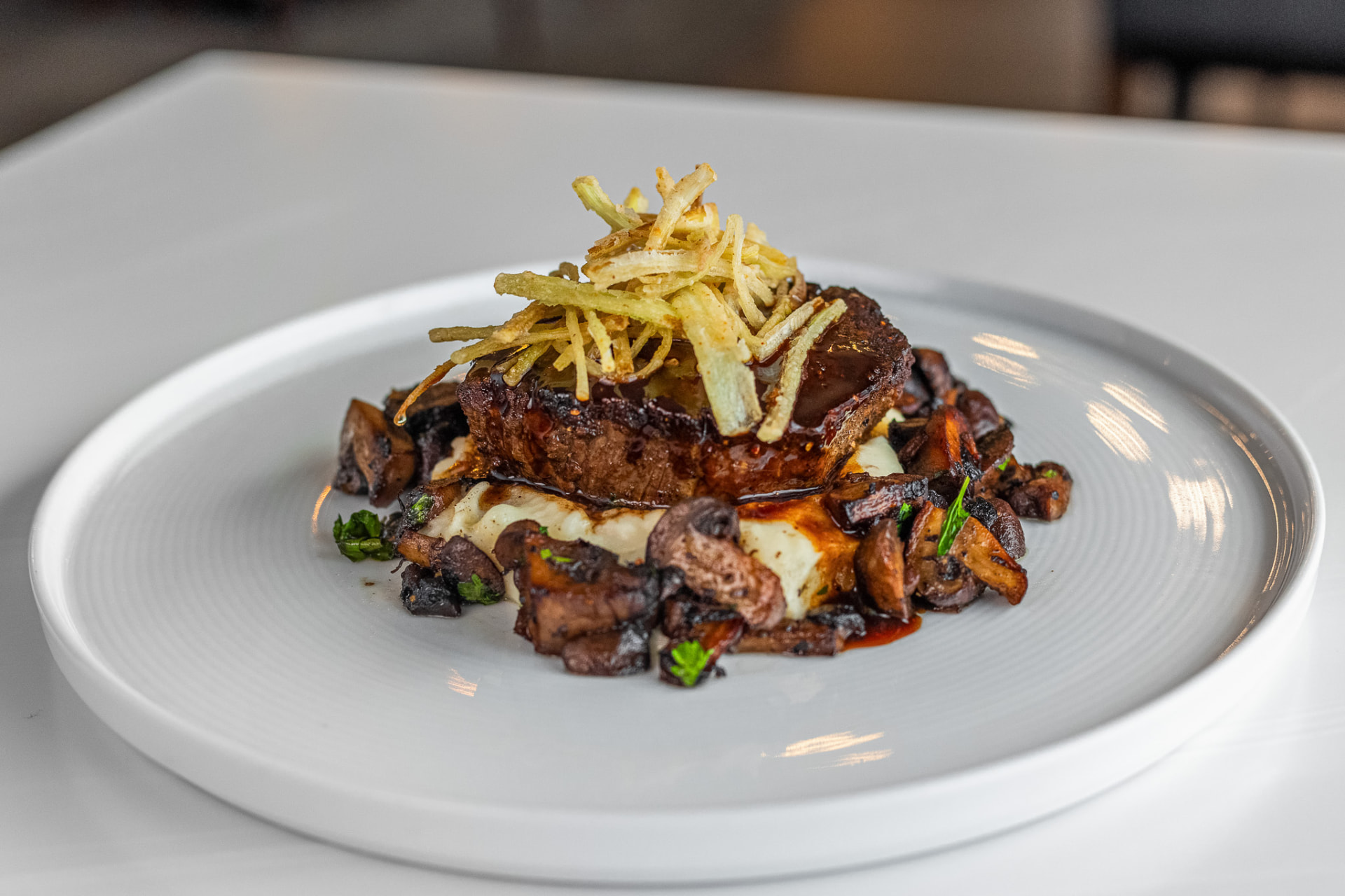 Seared steak over mushrooms and whipped potato topped with crisp shoestring potatoes