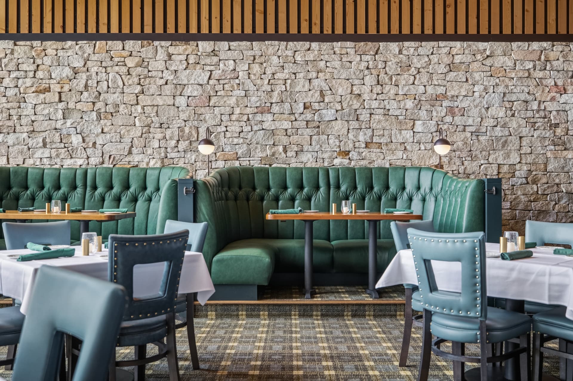 Green leather booth against a stone wall in the Fairchild dining room